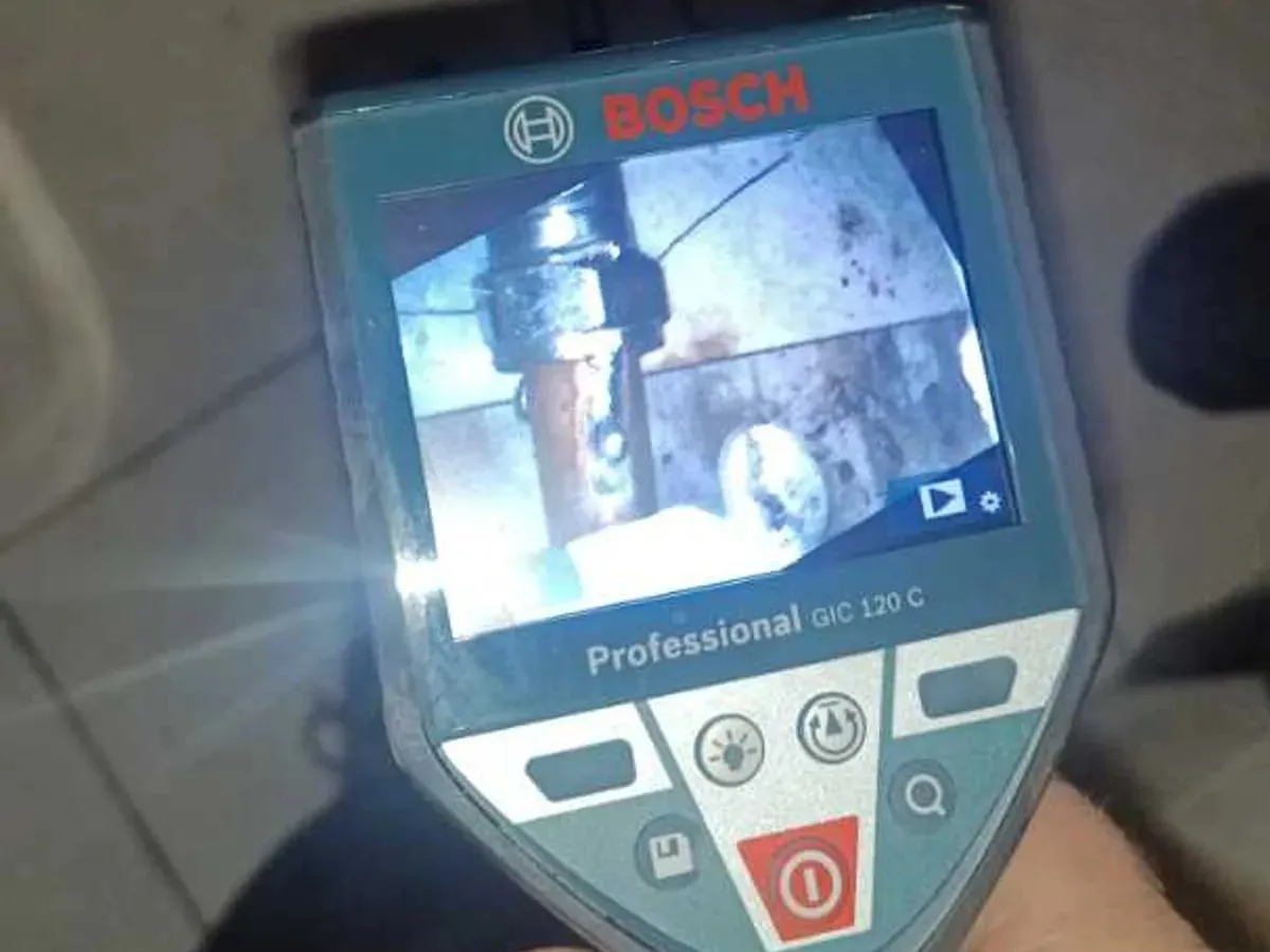 An endoscope camera screen shows a copper pipe connection inside a confined space