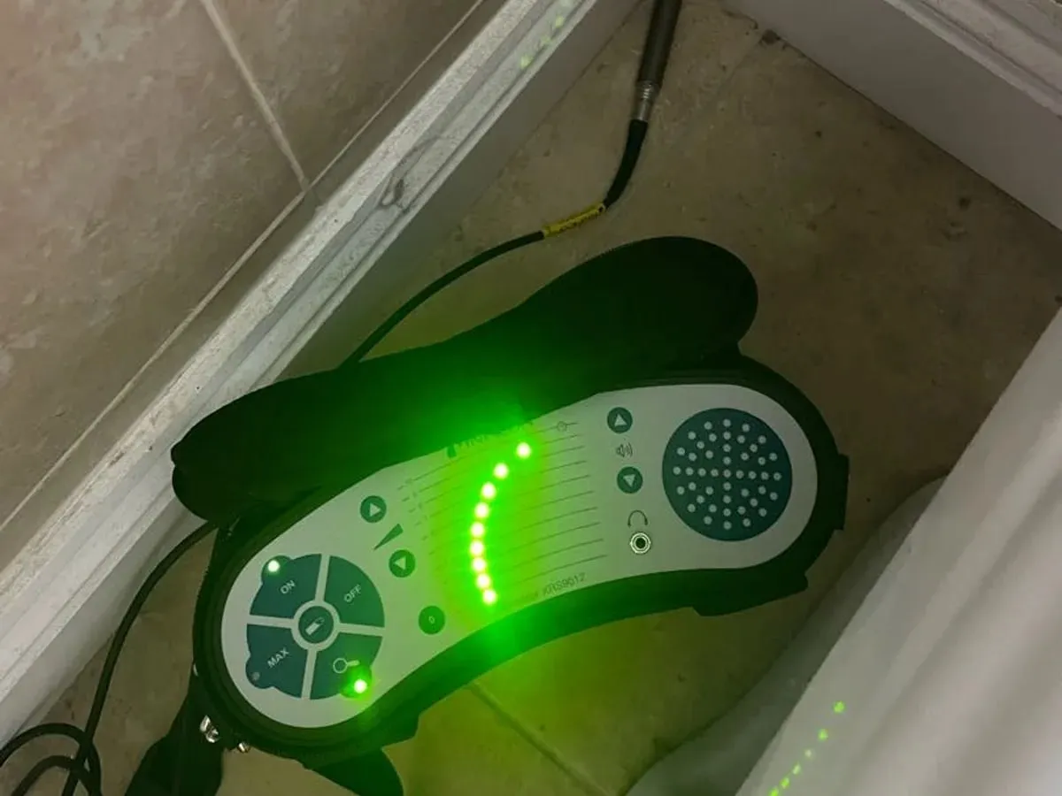 An illuminated tracer gas detector beside the tiled bathroom wall