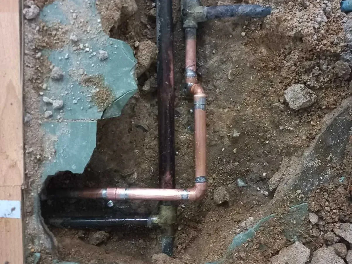 New copper pipe with an elbow and couplings installed in the opened floor