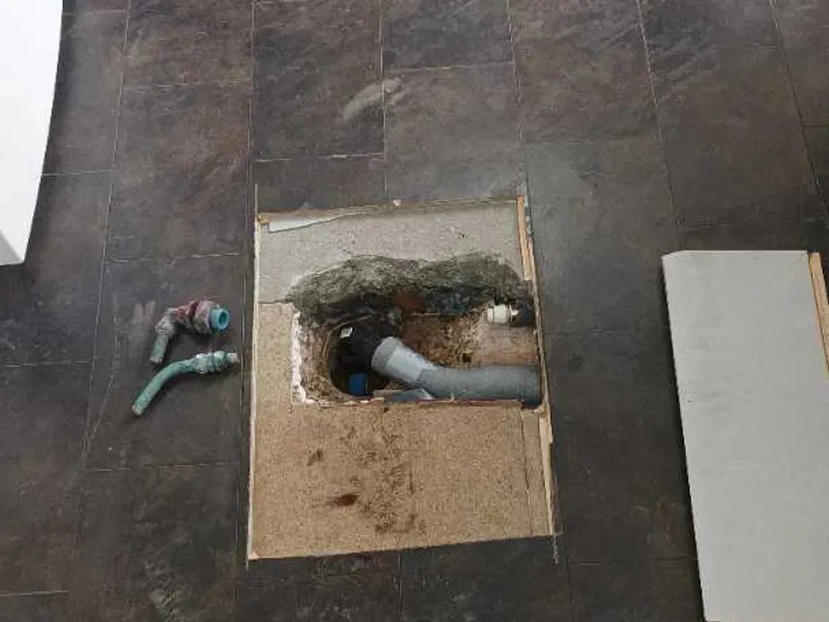 Replacement pipework and insulation visible through the rectangular kitchen-floor access opening
